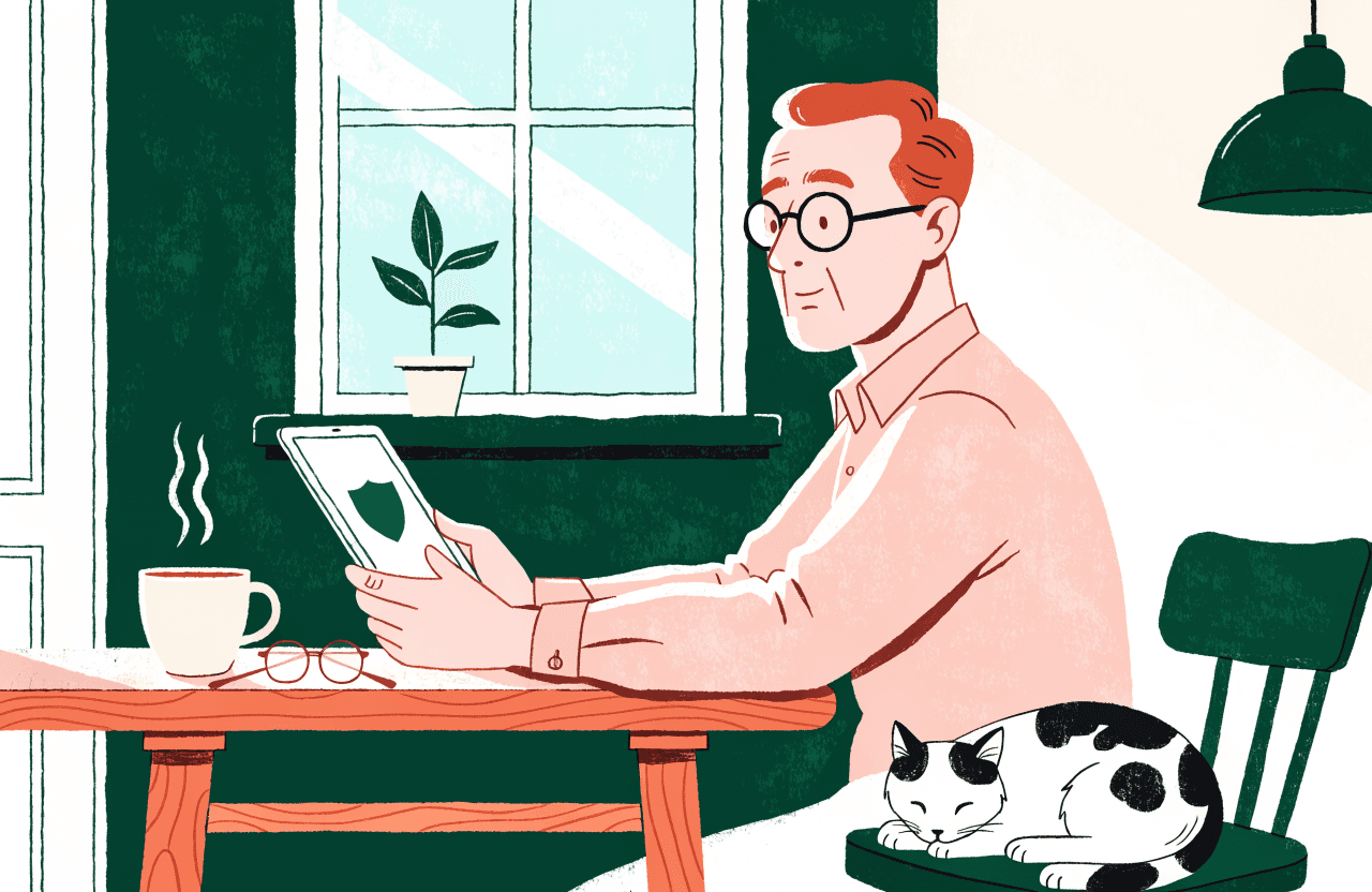 An older man calmly reading a message on his tablet at the kitchen table, his cat asleep beside him